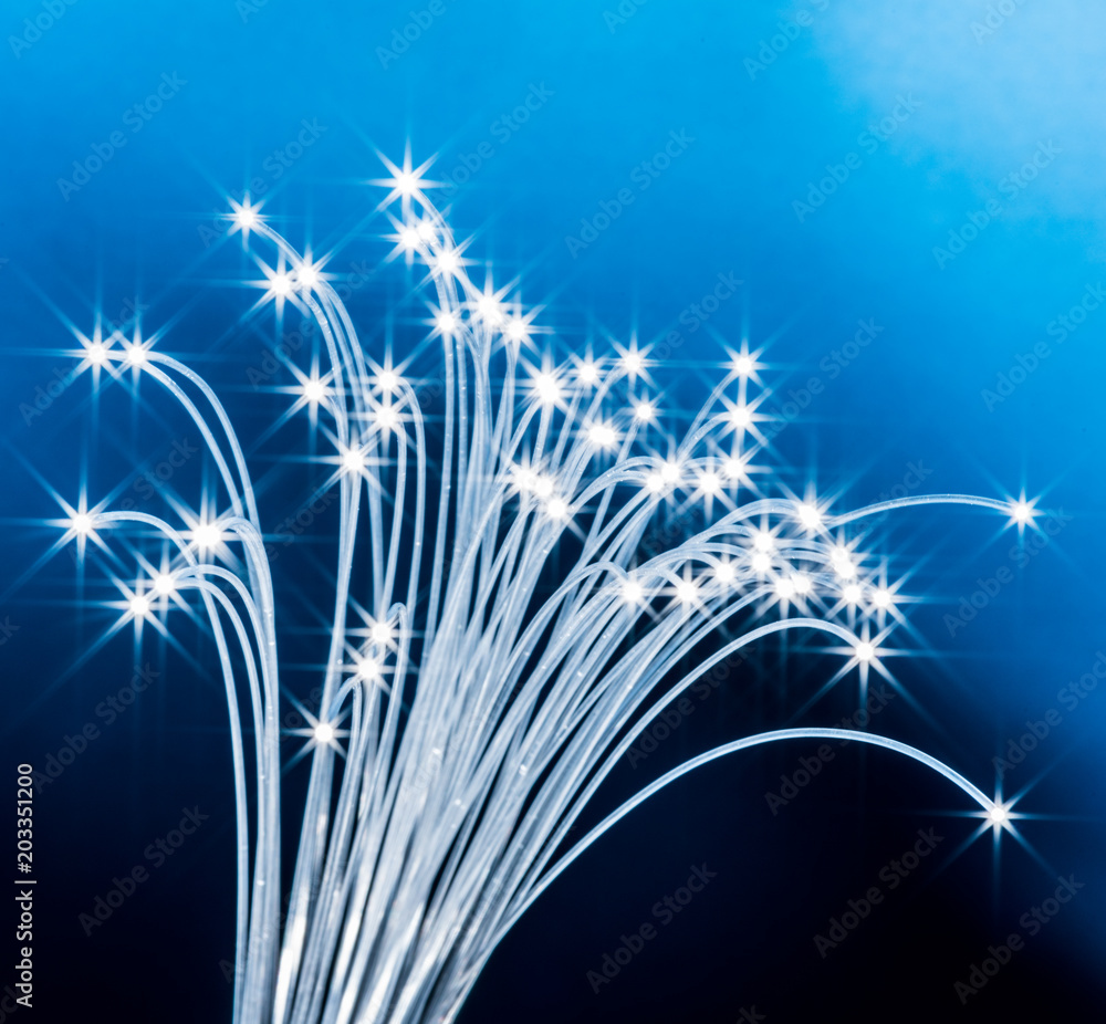 Naklejka premium Bundle of optical fibers with lights in the ends. Blue background.