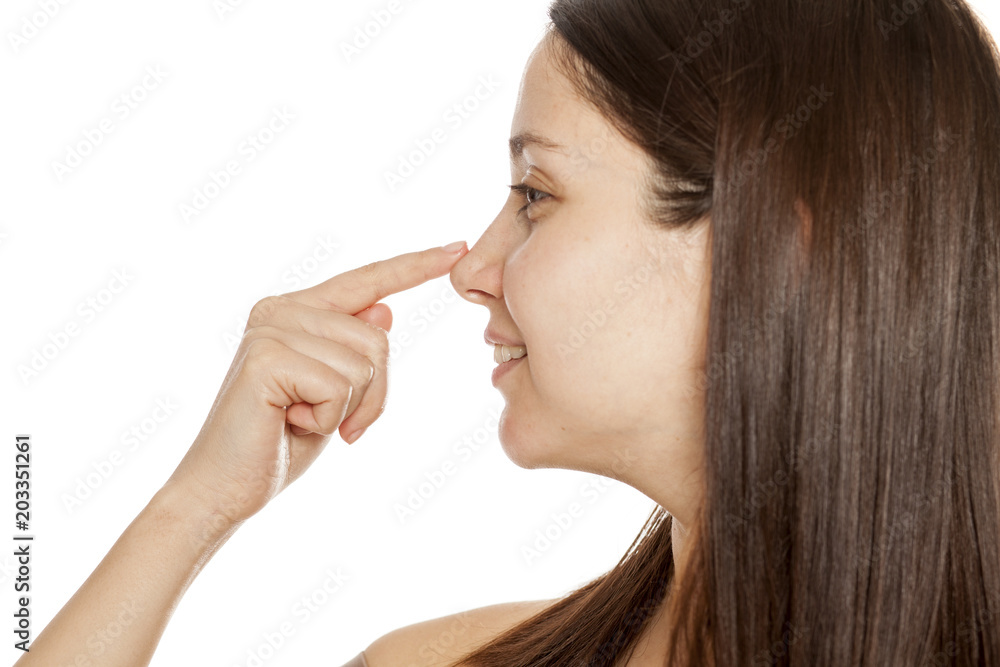 Profile of happy young woman touching her nose on white background Profile of happy young woman touching her nose on white background