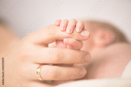 Female hand holding her newborn baby's hand. Mom with her child. Maternity, family, birth concept. Copy space for your text