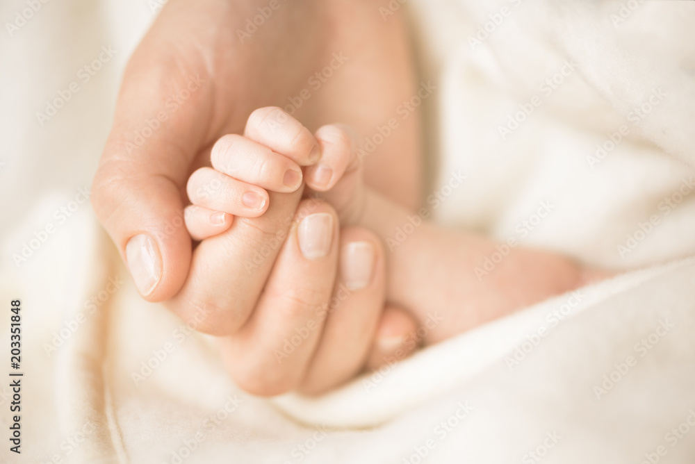 Female hand holding her newborn baby's hand. Mom with her child. Maternity, family, birth concept. Copy space for your text Female hand holding her newborn baby's hand. Mom with her child. Maternity, family, birth concept. Copy space for your text