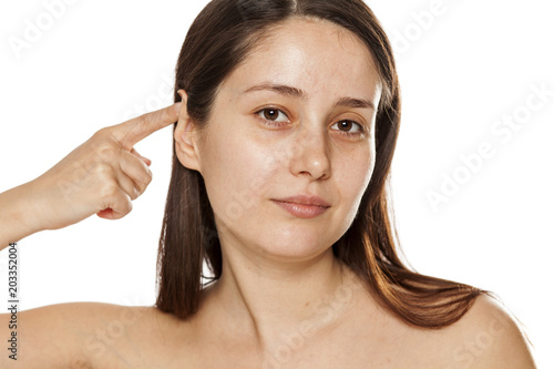 Beautiful young woman touching her ear on white background photo