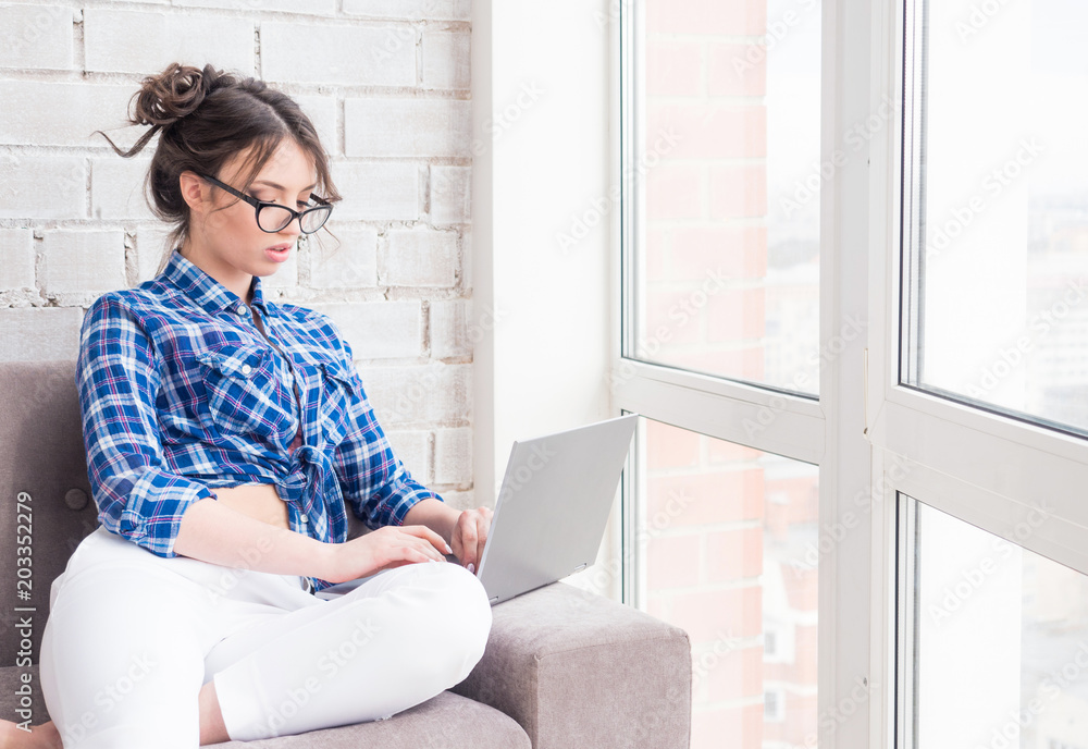 happy young woman in glasses sitting on the sofa and using a laptop computer at home happy young woman in glasses sitting on the sofa and using a laptop computer at home