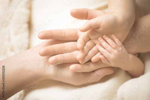 Newborn child hand. Closeup of baby hand into parents hands. Family, maternity and birth concept.