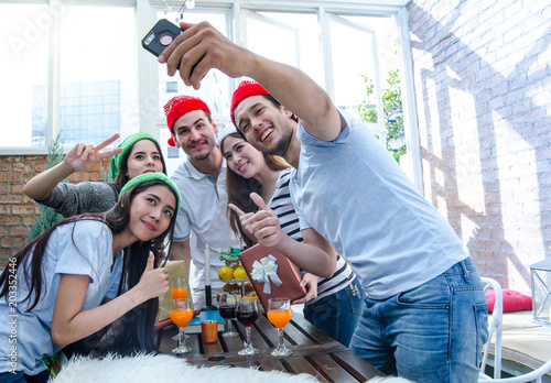 Group of friends shooting selfie and having fun in party time, with Christmas hat