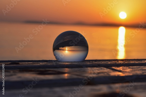 Glass sphere at the beach during sunset  conceptual image of summer holiday vacation 