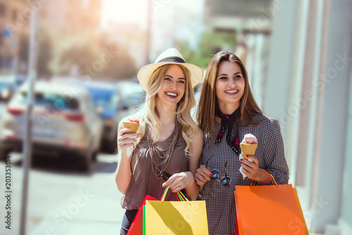 Happy young women with shopping bags and ice cream having fun on city street © Mediteraneo