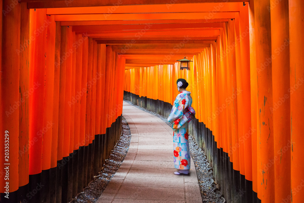 Fototapeta premium Kobieta w tradycyjnej kimonowej pozyci przy tunelem torii bramy, Japonia