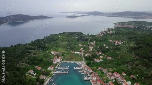 Aerial: Drone tilting up high over island Prvic in Croatia filming seascape. Showing beautiful blue marina and near by islands. Filmed on sailing trip in Adriatic sea in Croatia.