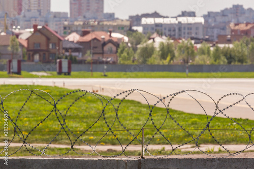 Empty airport runway in the background of the city. fence with barbed wire.summer photo