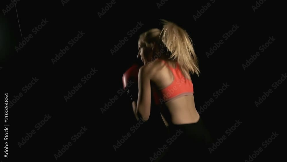 Slow motion of boxer shadow boxing. Young white woman in black background. Fighting sport fitness concept. Slow motion of boxer shadow boxing. Young white woman in black background. Fighting sport fitness concept.