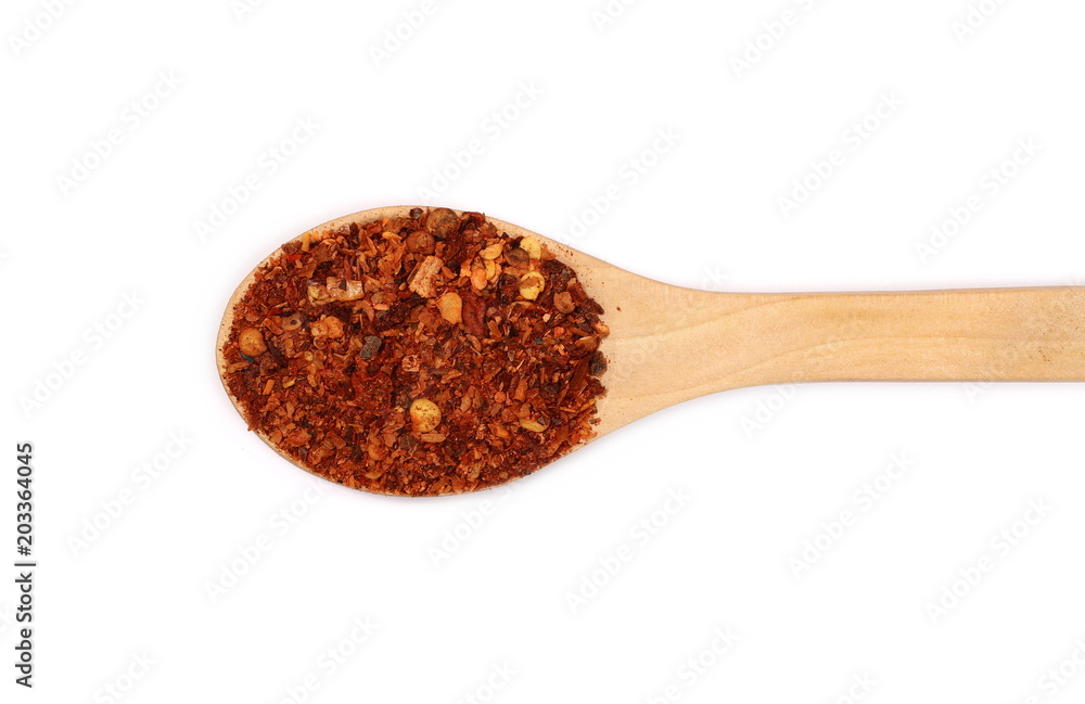 Crushed red cayenne pepper, dried chili flakes and seeds pile in wooden spoon isolated on white background, top view Crushed red cayenne pepper, dried chili flakes and seeds pile in wooden spoon isolated on white background, top view