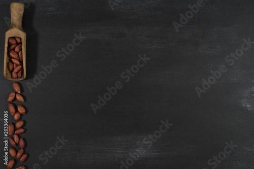 Peanuts in a scoop on a black chalkboard.