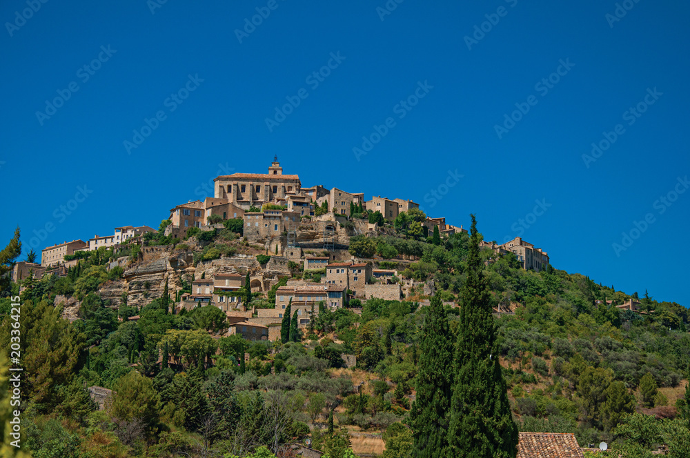 Panoramic view of the village of Gordes on top of a hill and under sunny blue sky. Located in the Vaucluse department, Provence region, southeastern France