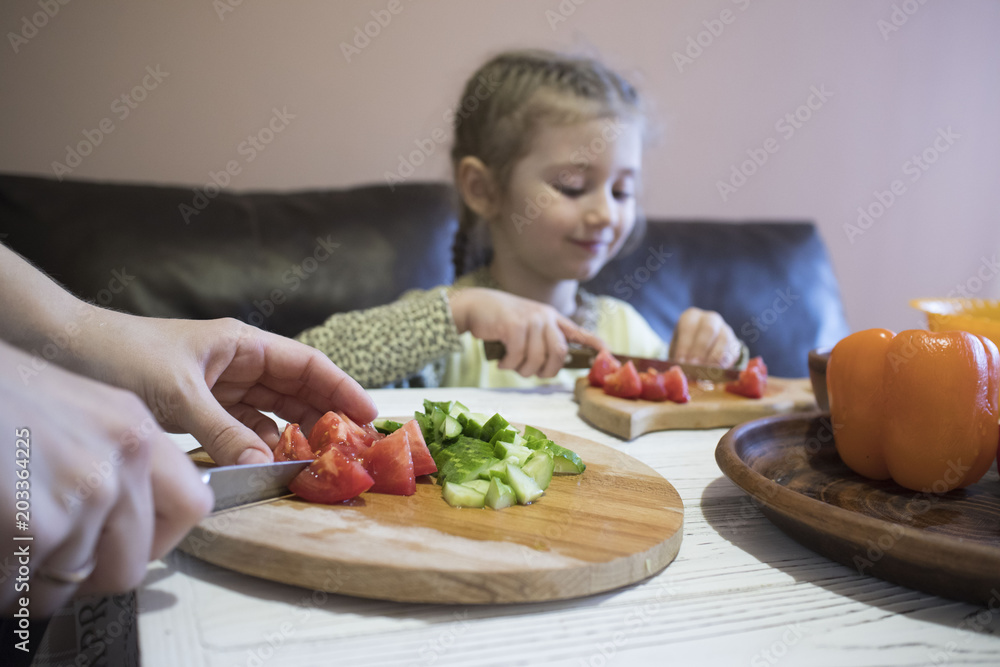 mom and daughter cut salad in the kitchen mom and daughter cut salad in the kitchen