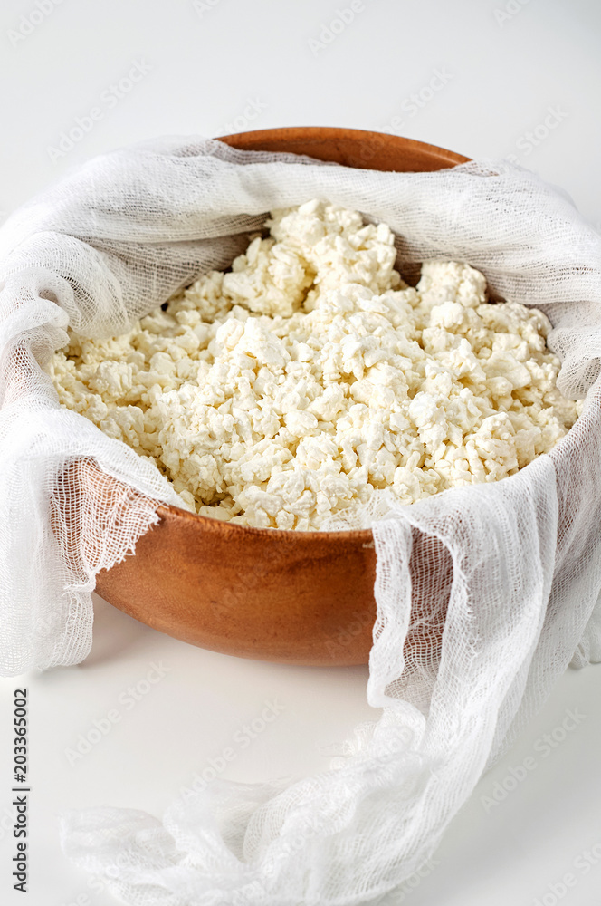 Preparation fresh cottage cheese with cheesecloth in wooden bowl