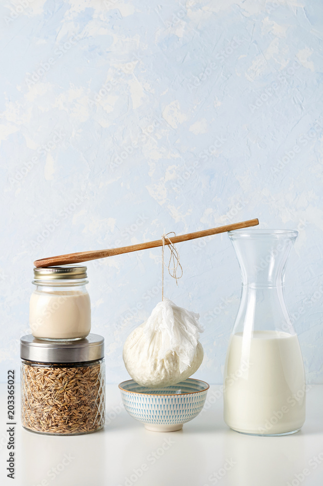 Preparation fresh cottage cheese. The curds in strainer to drain from a wooden spoon between two stacks of glass