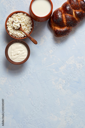 Challah bread with poppy seeds and set of dairy products comprising cottage cheese, sour cream and whole milk