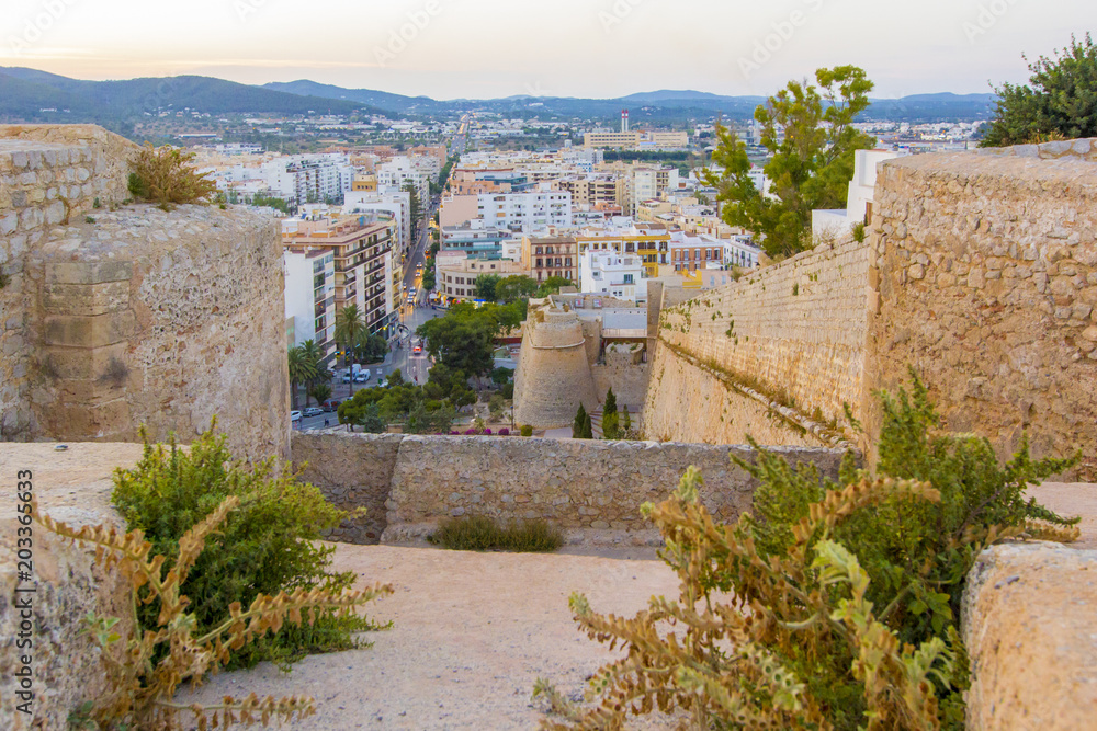 Panoramic view from medieval fortress on old town, streets and roofs of houses and mountains of Ibiza Town, Balearic Islands, Spain