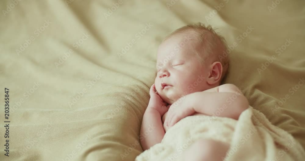 newborn Caucasian baby boy two weeks age toddler sleeping on bed, close-up newborn Caucasian baby boy two weeks age toddler sleeping on bed, close-up