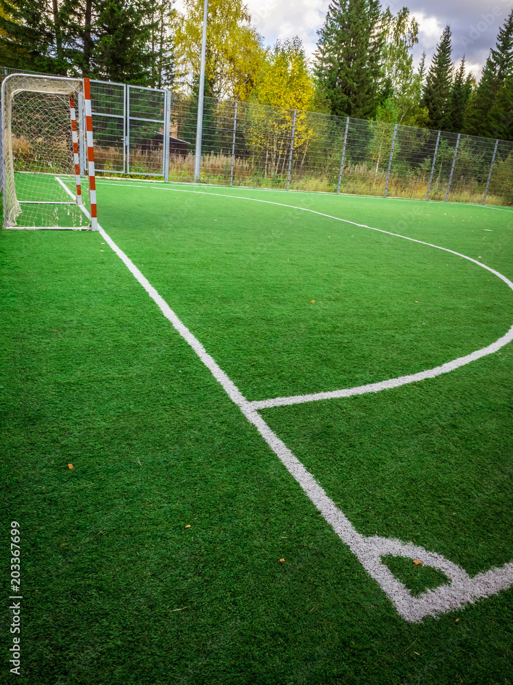 Fototapeta premium Corner of a soccer. Soccer field with green grass yard and football goal in school area. beautiful sport playground.