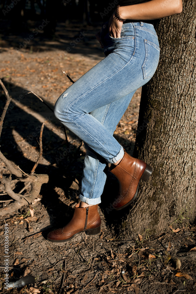 Ud over Total Gud Brown shiny leather womens chelsea boots on woman legs with blue jeans in  autumn forest or park. Stock Photo | Adobe Stock