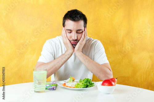 young man seating at the table and looking at his healthy meal