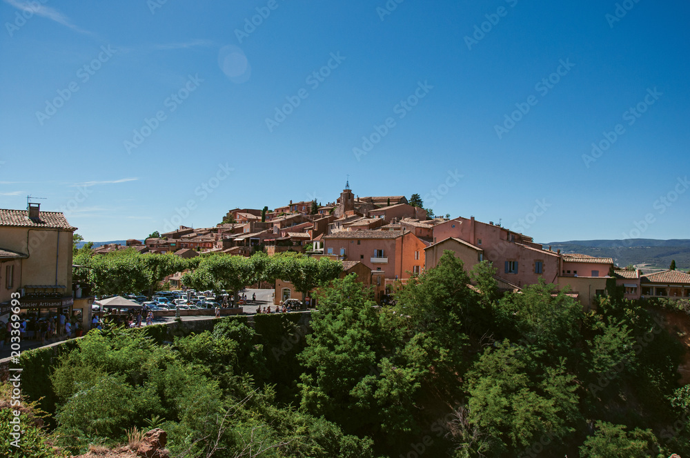 Panoramic view of the village of Roussillon and surrounding woods, under a sunny blue sky. Located in the Vaucluse department, Provence region, in southeastern France