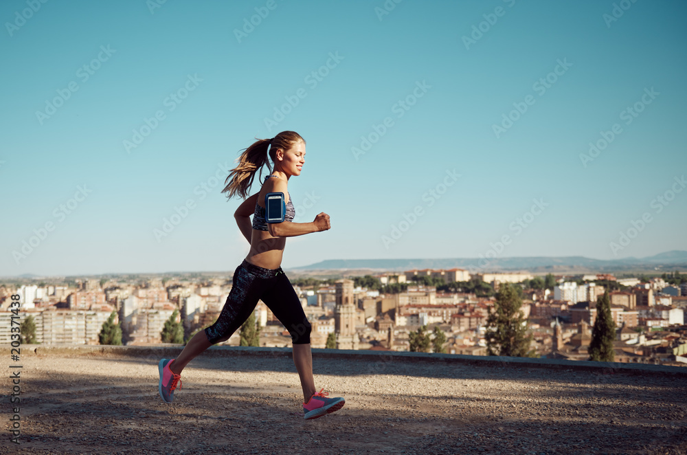 Young female jogger training outdoor at sunset. Concept of sport and active lifestyle. 