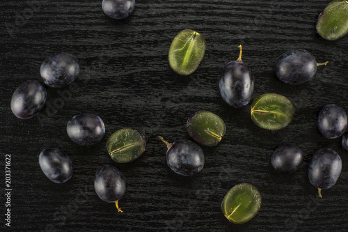 Black grape berries (autumn royal variety) table top isolated on black wood background some sliced. photo