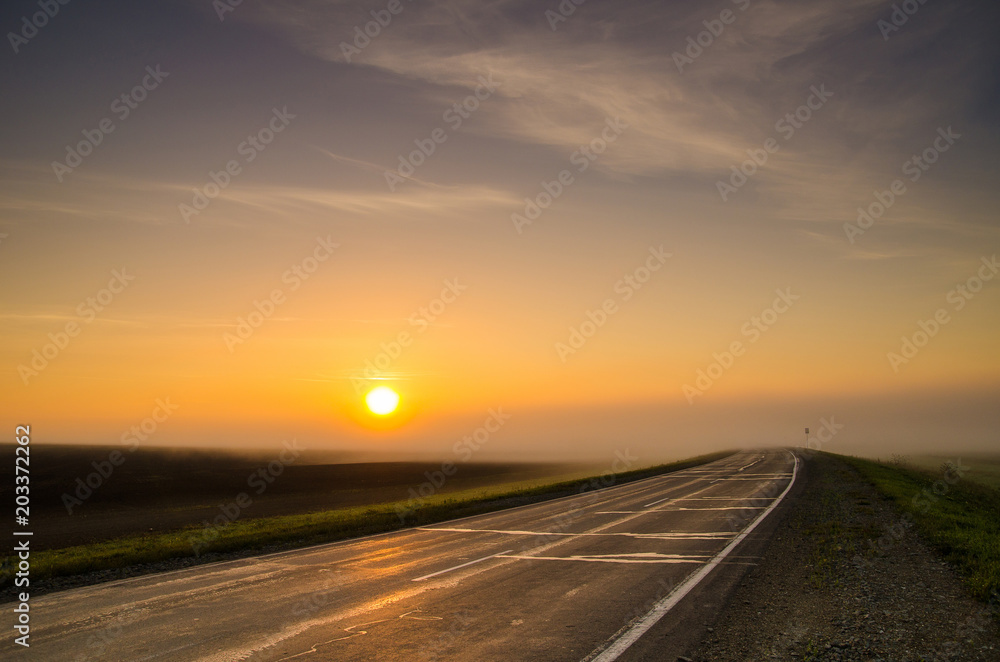 The disk of the sun rising in the early morning fog in rural areas