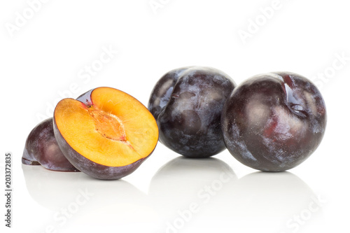 Two red blue plums and two sliced halves isolated on white background.