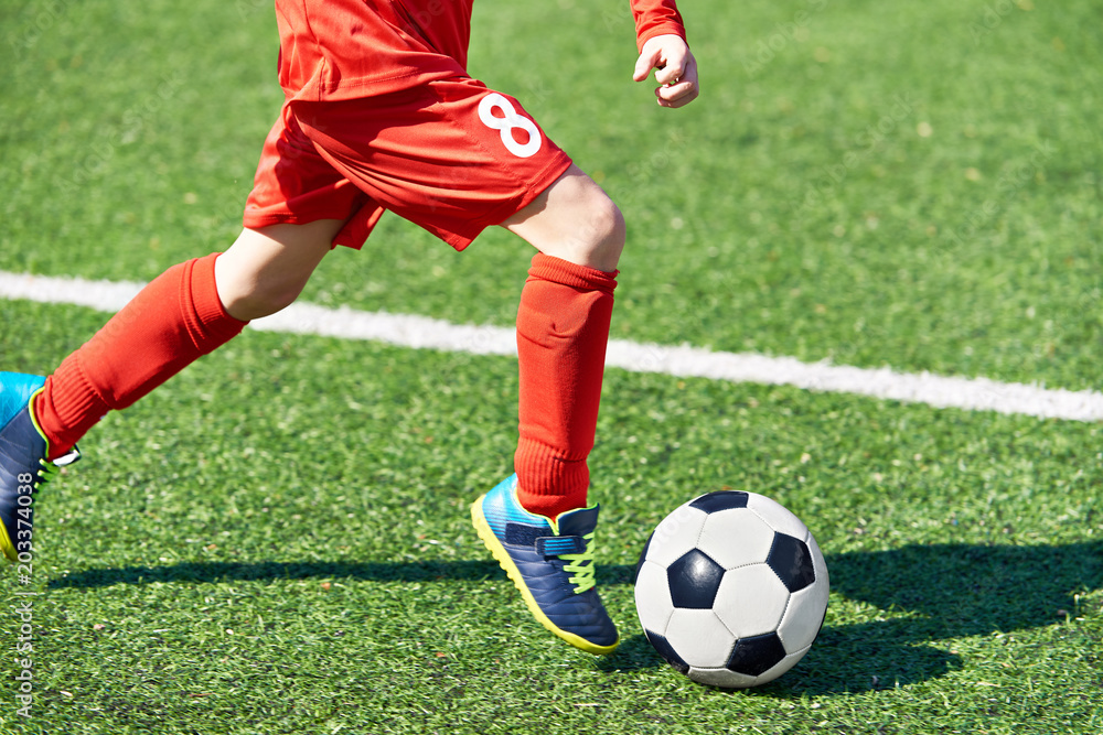Child soccer player and ball on football field