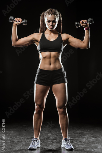 Fitness girl with dumbbells on a dark background isolated