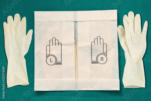 Disposible sterile rubber,one time used Gloves with paper package on green signature of surgery dress