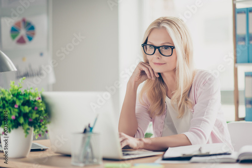 Foto Nice, cute, confident, charming middle aged headmistress sitting at desk in work