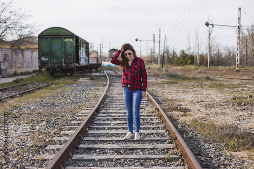 young beautiful woman wearing casual clothes, walking by the railway and smiling. Outdoors lifestyle. Travel concept.