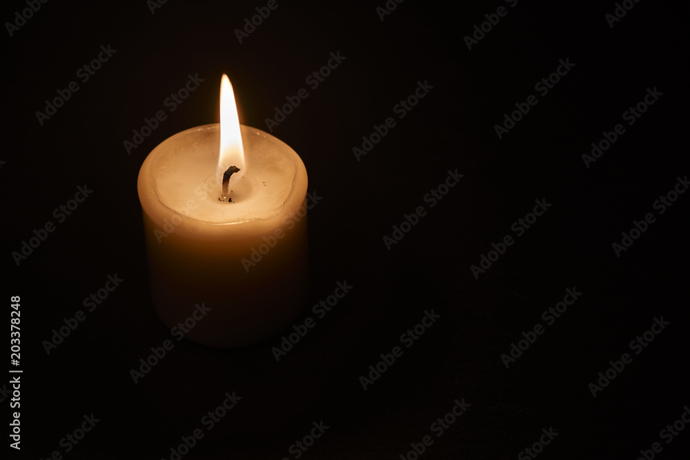 a burning candle in the dark