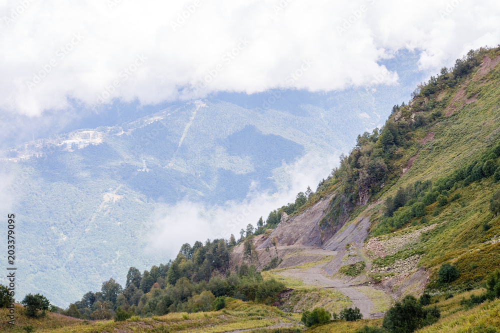 Photo of mountain slopes with vegetation and cloudy sky