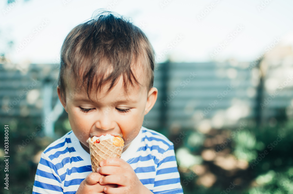 a child in a t-shirt on a bench eating ice cream in the summer is very greedy a child in a t-shirt on a bench eating ice cream in the summer is very greedy