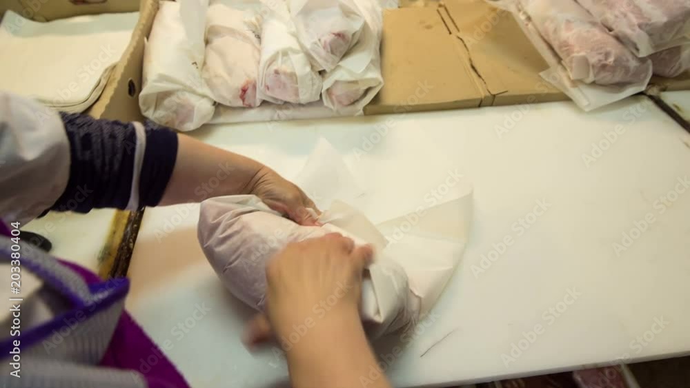 The first person, the woman wraps pork tenderloin in the paper for sale The first person, the woman wraps pork tenderloin in the paper for sale