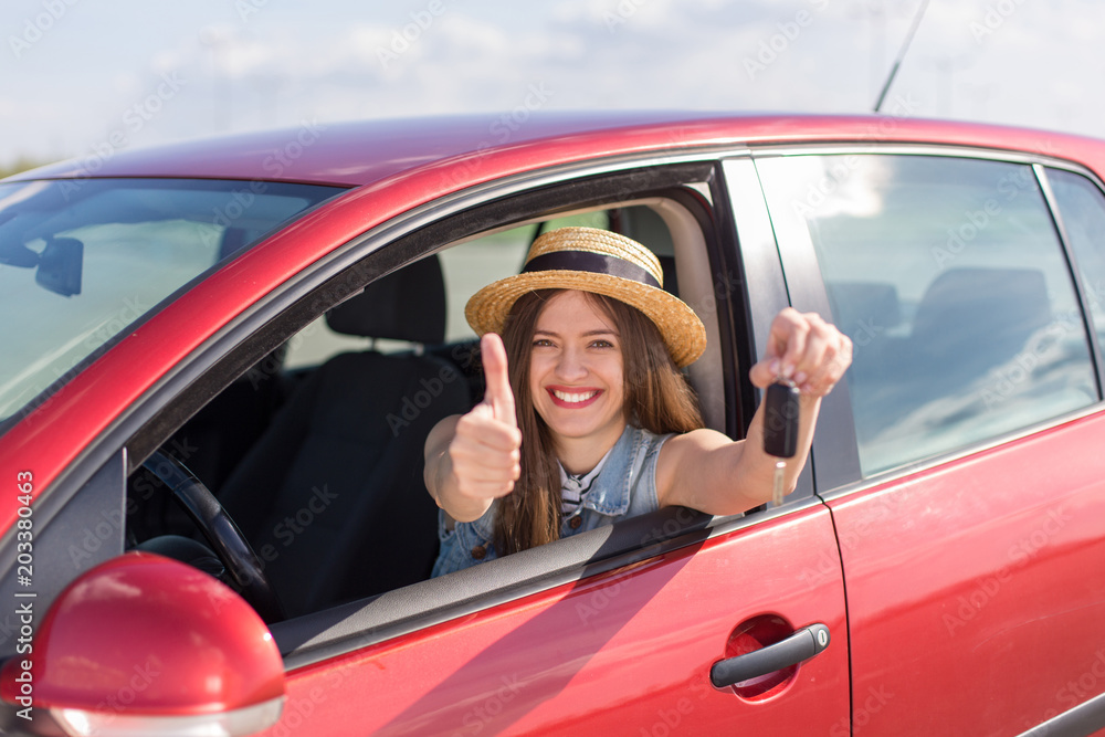 Driver woman smiling showing new car keys and car. Happy woman driver showing car keys and leaning on car door
