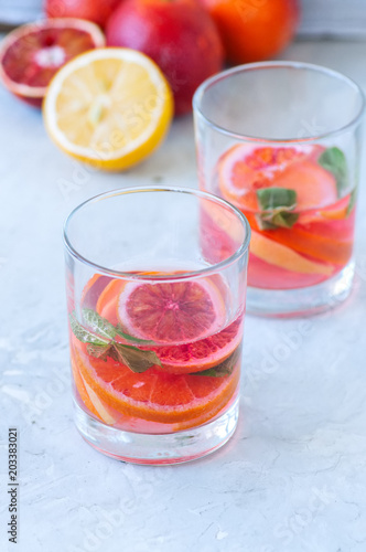 Refreshing blood orange water or infused water in a glass on a wooden background.
