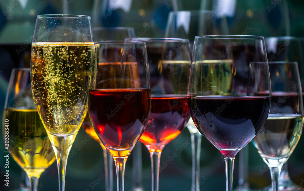 Fototapeta premium Champagne, white, rose and red wins and drinks in glasses on stained glass background