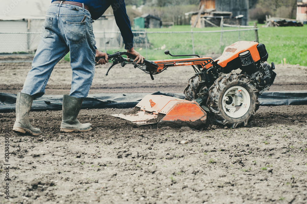 farmer with motor cultivator prepares the ground in spring farmer with motor cultivator prepares the ground in spring