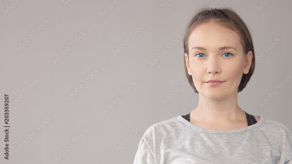 Closep portrait of midage caucasian woman on grey watching at camera Closep portrait of midage caucasian woman on grey watching at camera