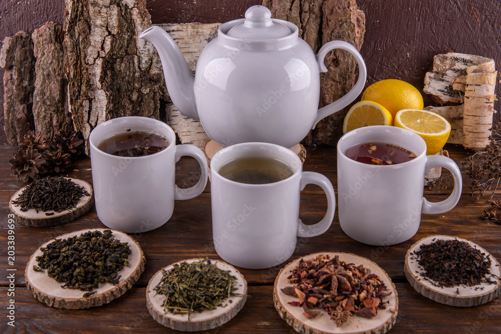 A cup with green tea, a cup with red tea and a cup with black tea, a big teapot, lemons on a dark wooden background
A cup with green tea, a cup with red tea and a cup with black tea, a big teapot, lemons on a dark wooden background
