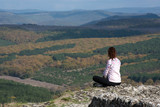 the girl sits on a cliff and looks into the distance