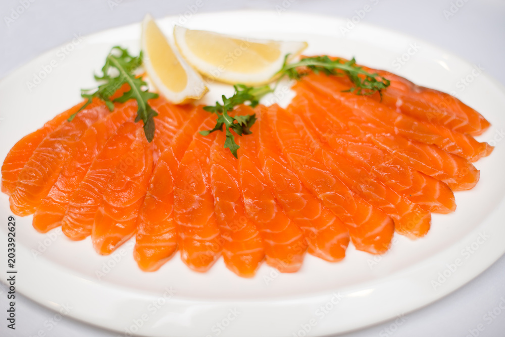 red sliced fish on plate withlemon on white background. red sliced fish on plate withlemon on white background.