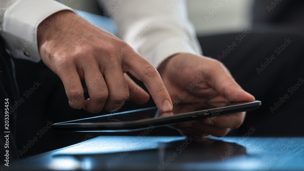 Businessman navigating a tablet computer activating the touchscreen with a finger Businessman navigating a tablet computer activating the touchscreen with a finger