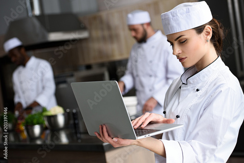 beautiful chef using laptop at restaurant kitchen
